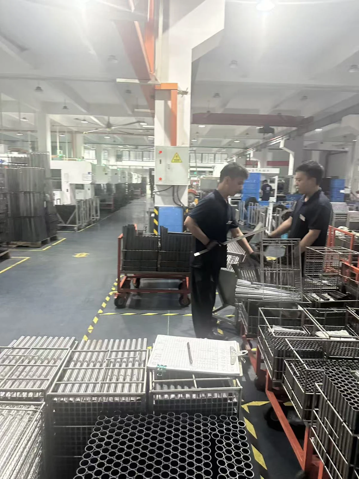 Workshop staff beside batches of metal tubes